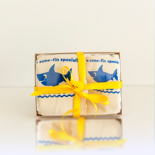 Box of baby washcloths with shark design and yellow ribbon on a light background