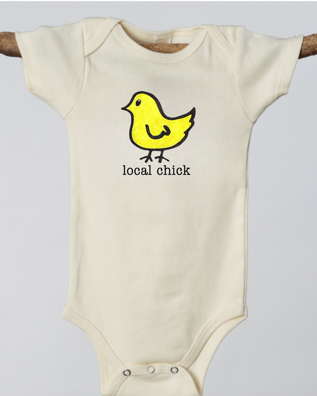 Off white baby onesie with a yellow chick graphic and 'local chick' text