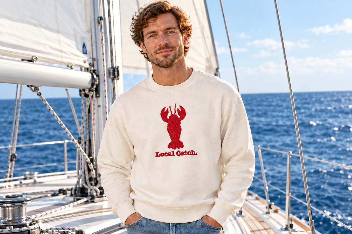 Man on a sailboat wearing the sweatshirt with the embroidered lobster design