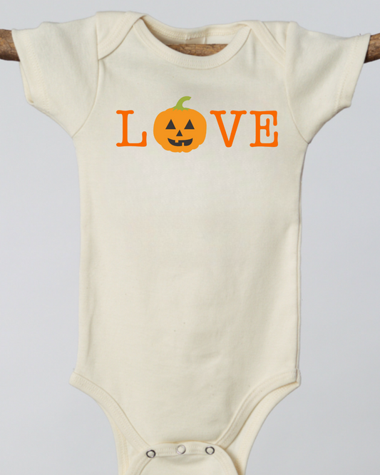 Beige baby onesie with 'LOVE' printed in orange, featuring a pumpkin design on a light gray background.