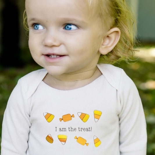 Child wearing a onesie with candy-themed design and text outdoors.