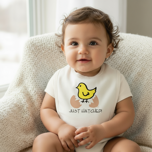 Latin baby girl wearing Just Hatched bib with off-white onesie