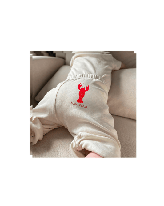 White baby onesie with a red lobster design.